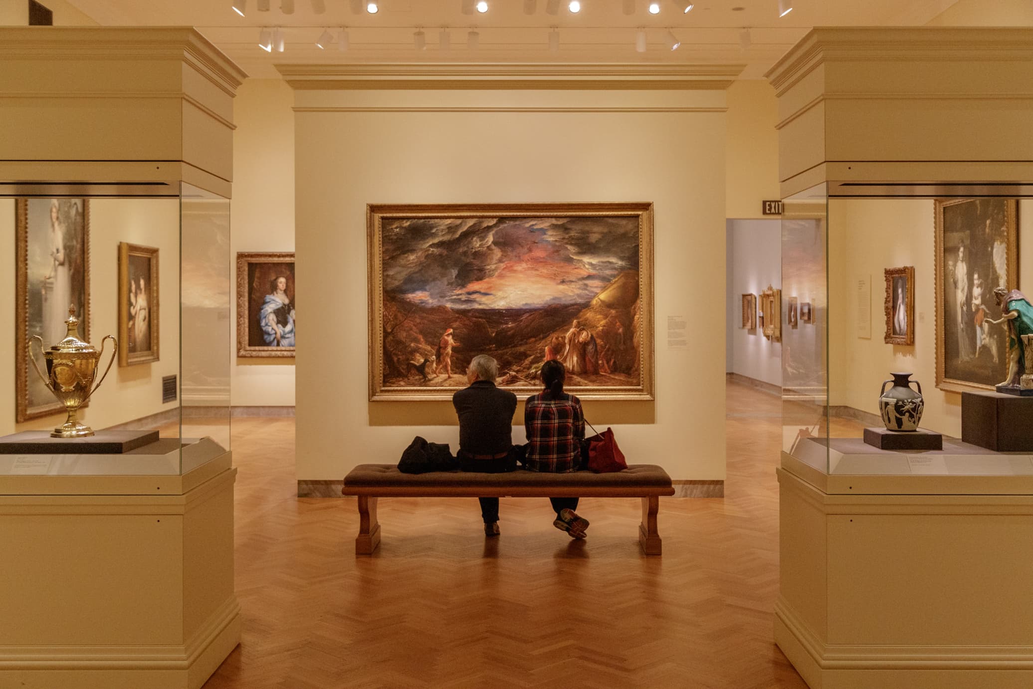 People sitting on a bench looking at art