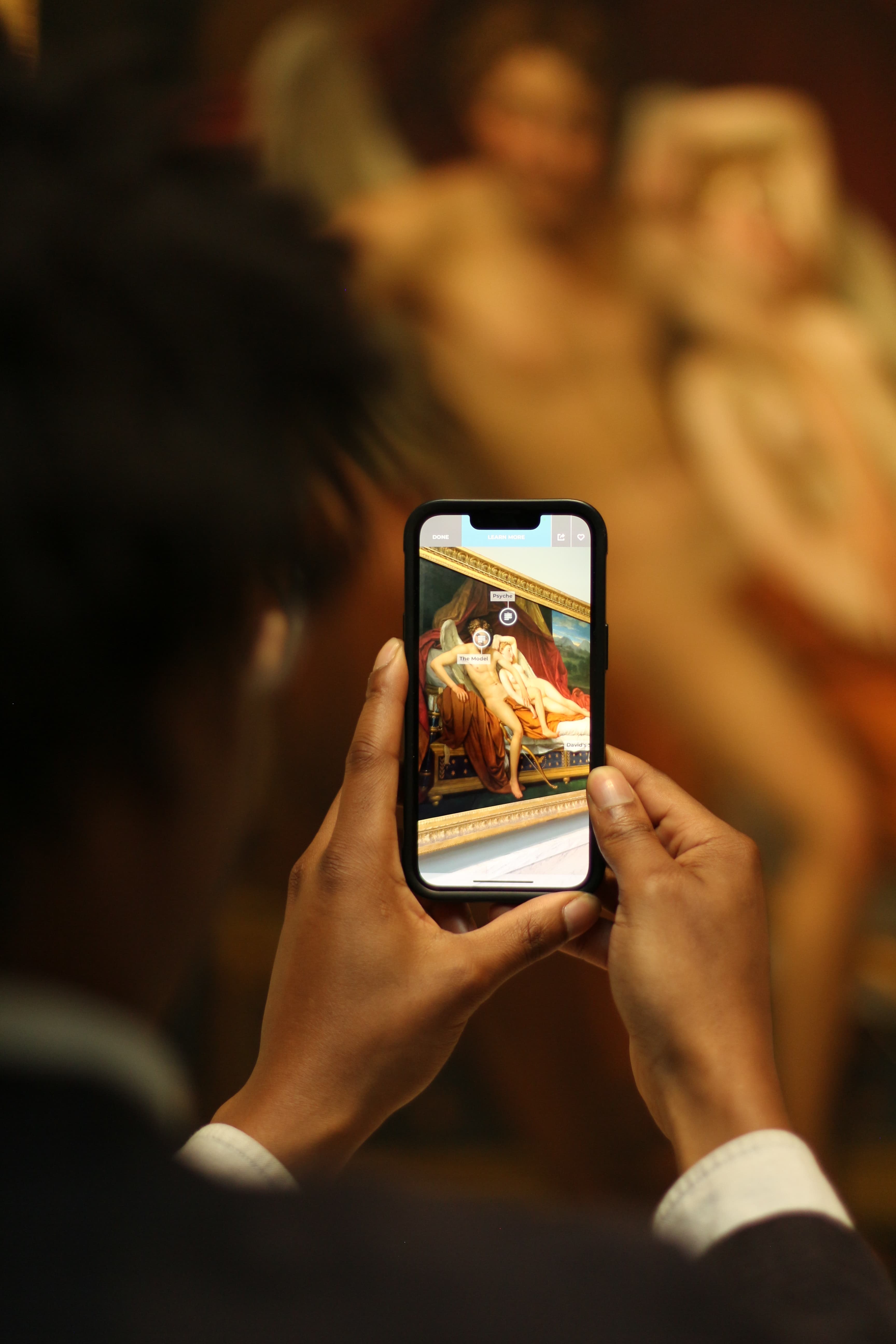 A hand holding a phone up to a painting.