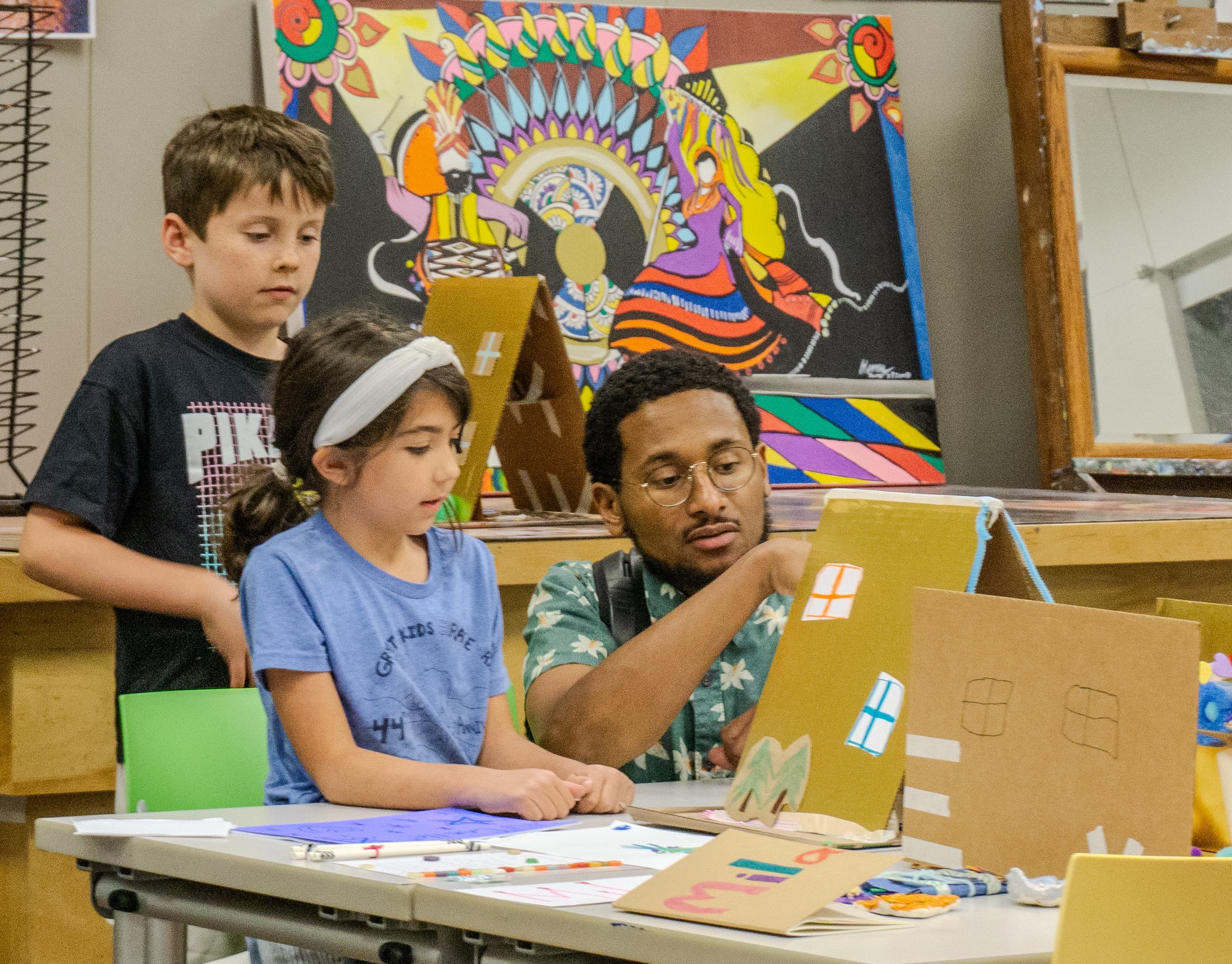 Adult and children making artwork together at a table.