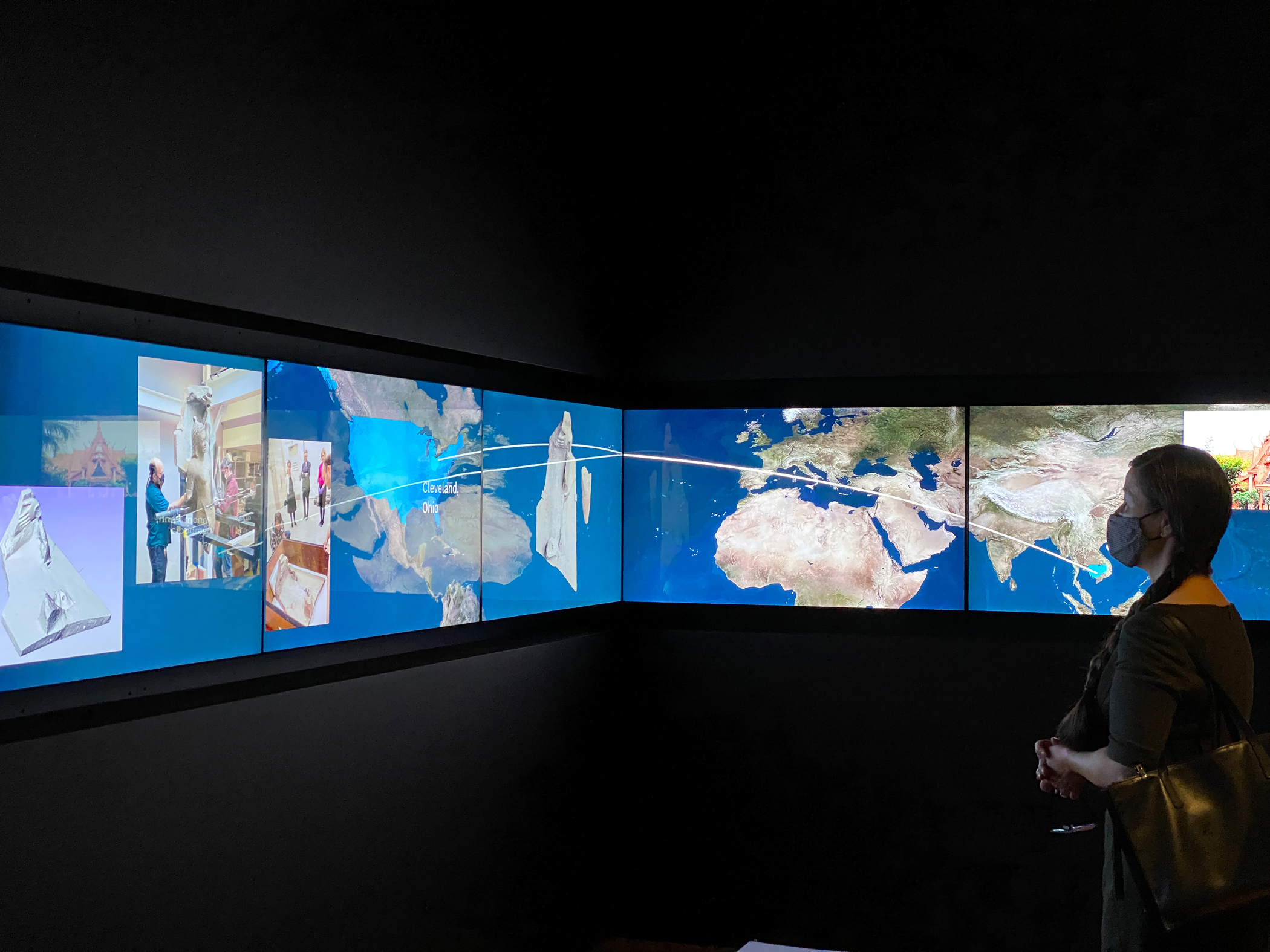 person views a panoramic configuration of screens with maps on them