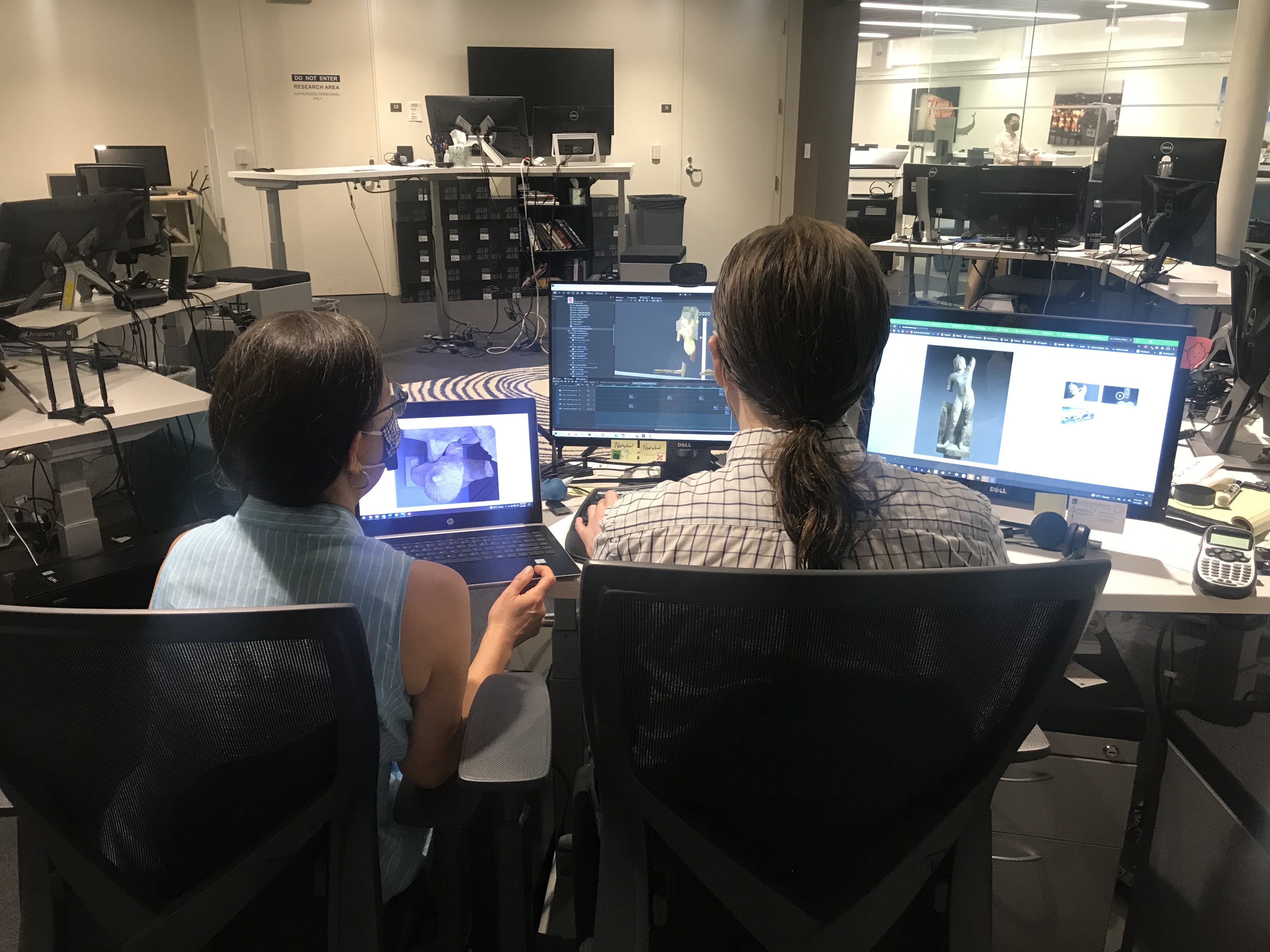 two people sitting in front of computers discussing images