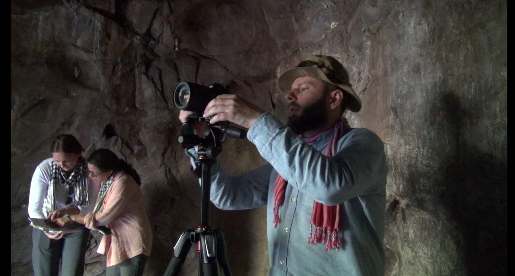 a man operating a camera in a cave