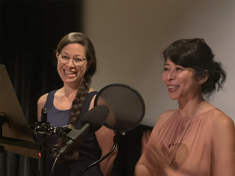 Two women in front of a microphone smiling