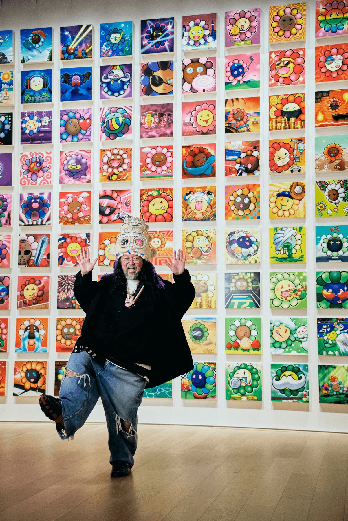 An artist posing in front of a wall of their art